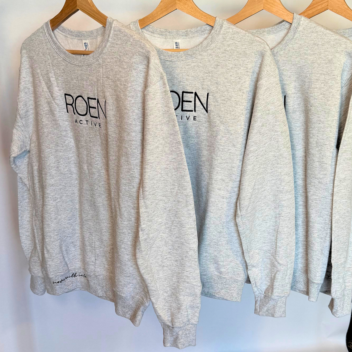 Gray sweatshirts with 'ROEN ACTIVE' logo on hangers against a white background