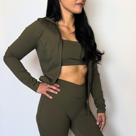 Woman wearing an olive green athletic outfit against a plain background