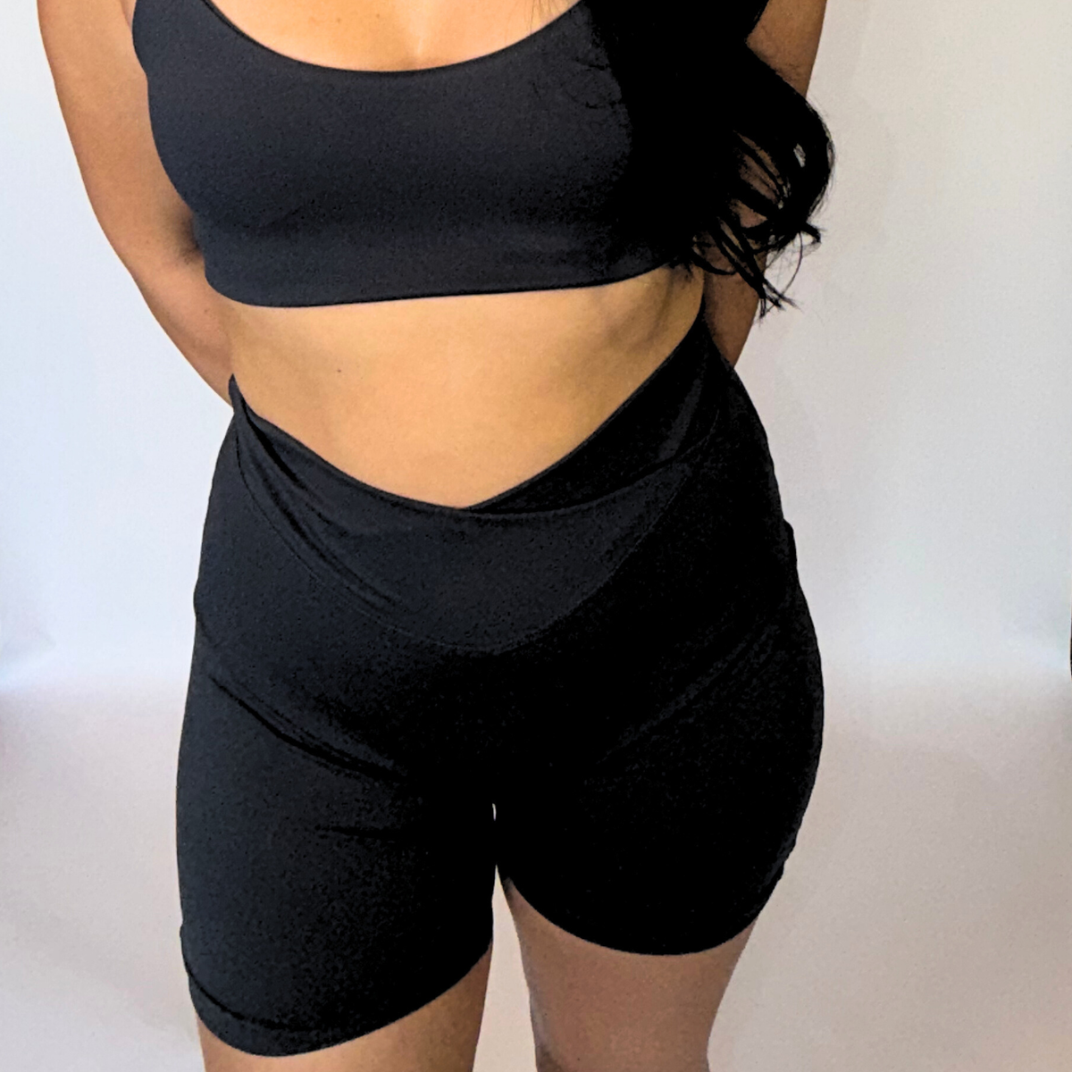 Person wearing a black sports bra and shorts on a white background
